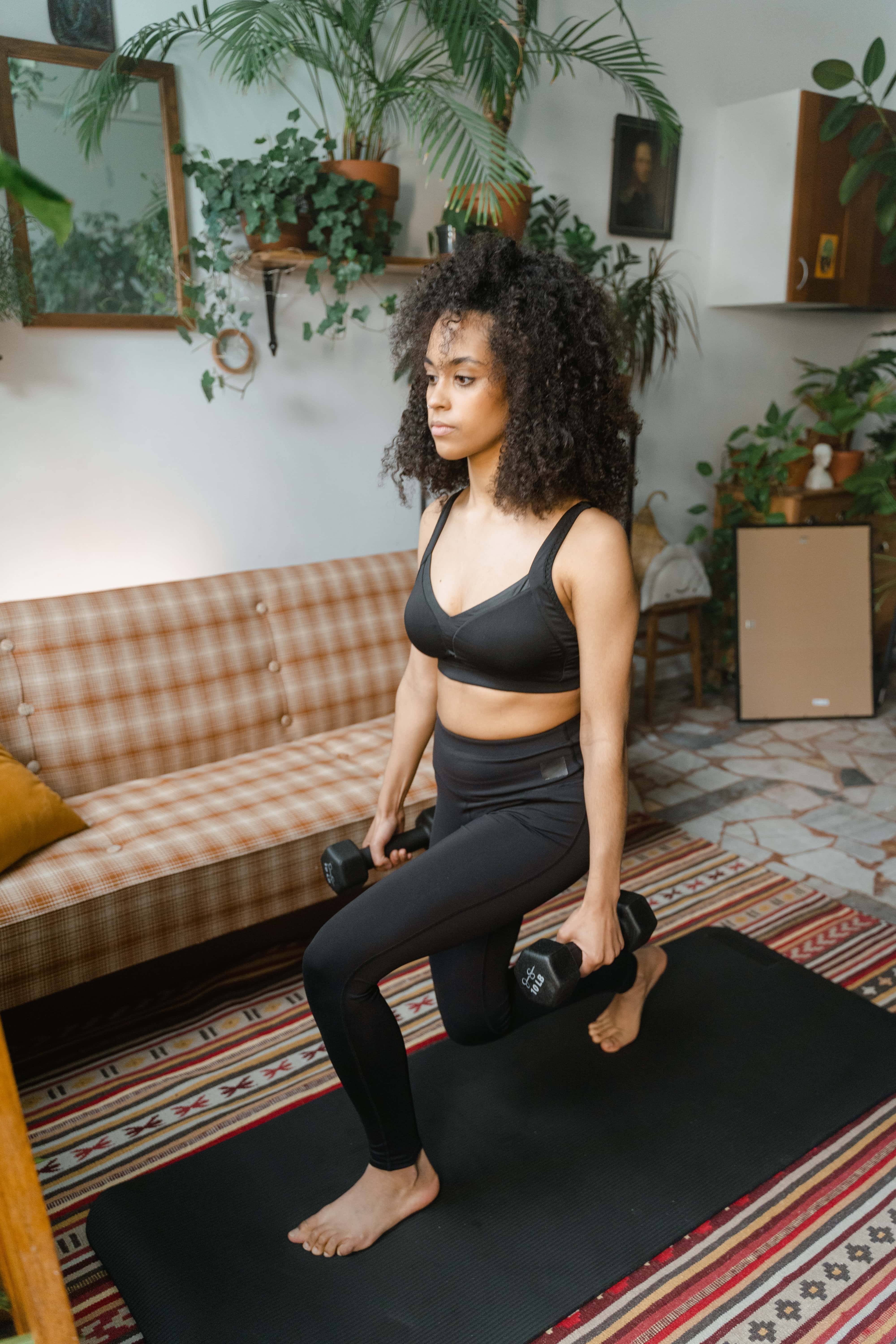 woman doing dumbbell lunges at home on mat